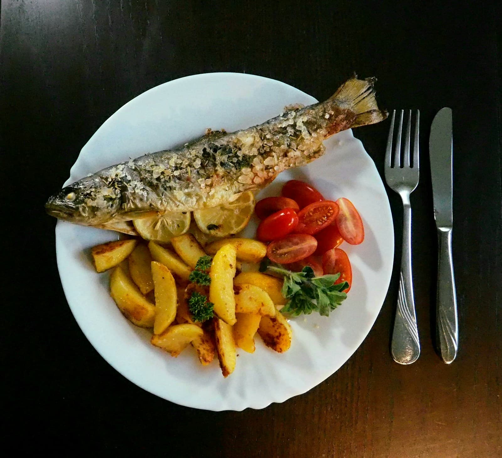 Whole roasted fish with potatoes, tomatoes, and herbs