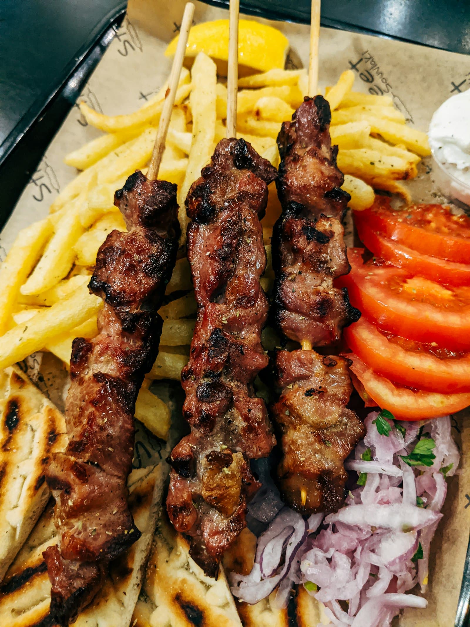 Grilled lamb skewers with pita, tomatoes, and onion