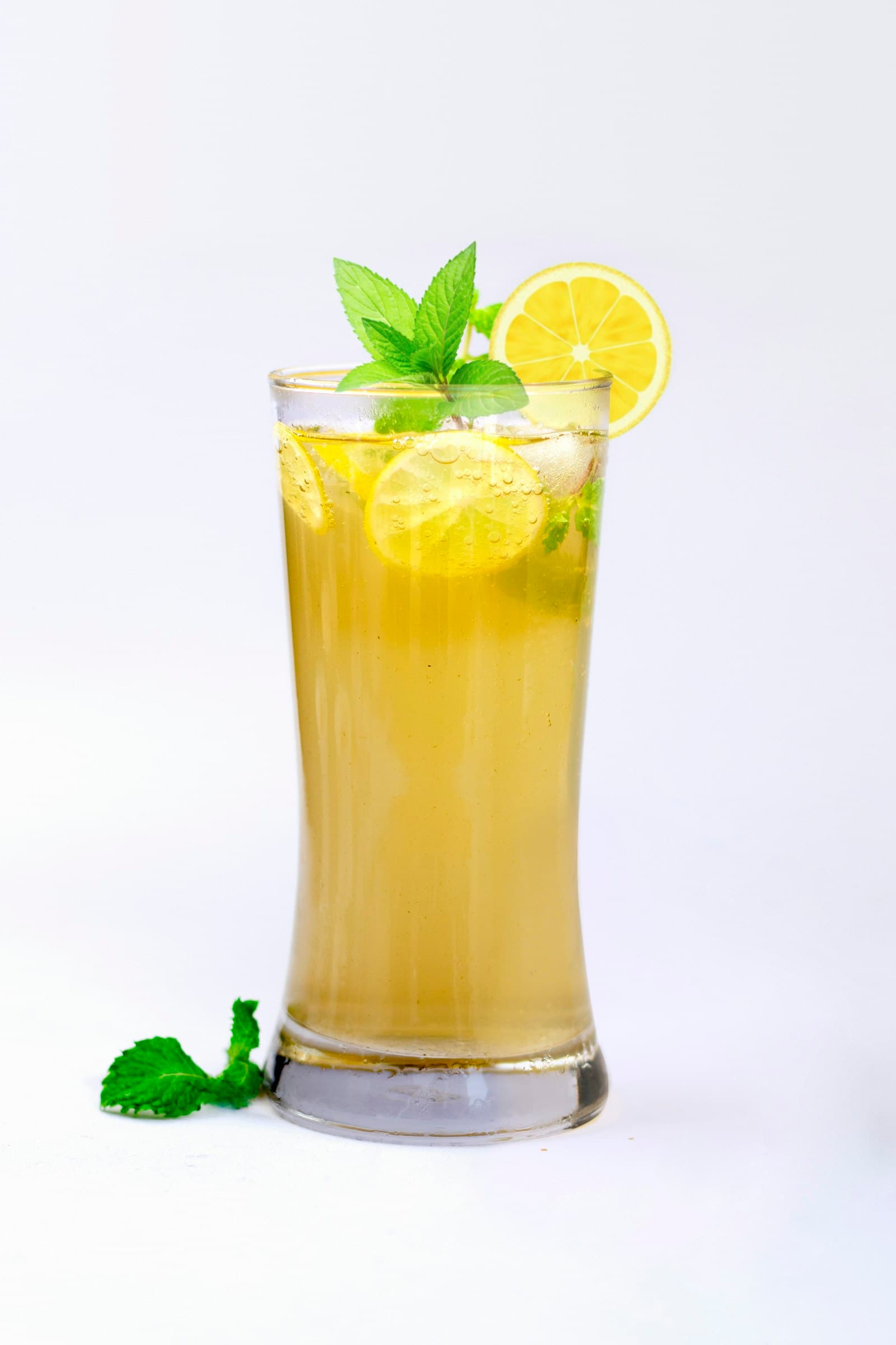 A tall glass of mint lemonade with lemon slices